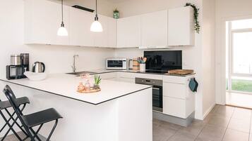A modern kitchen with white cabinets, a central island, a microwave, a coffee maker, and a sink.