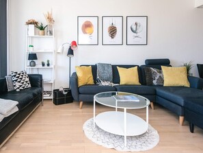 A modern living room with a dark blue sofa, a round glass coffee table, and a white floor lamp. - 5 Star Holiday Home in Ringkobing (Ringkobing)