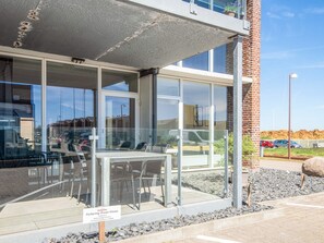A modern building with large windows, a covered outdoor seating area, and a sign indicating the location as 'Parker Center Ocean House.'