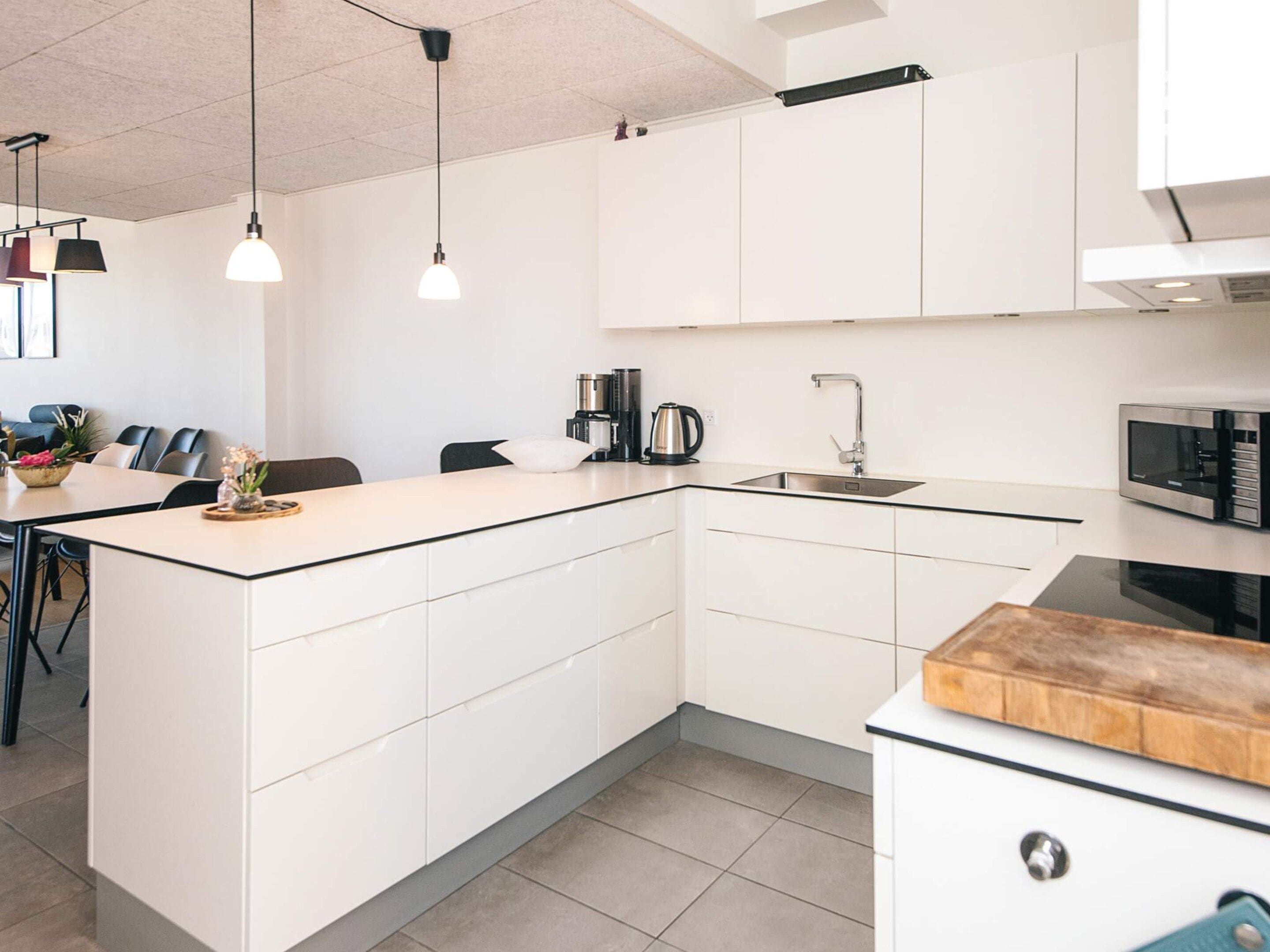 A modern kitchen with white cabinetry, a central island, a sink, and a microwave.