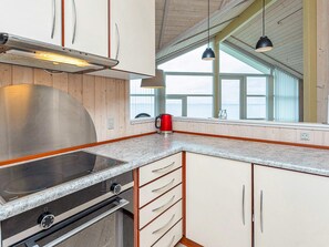 A kitchen with a stainless steel range hood, a built-in oven, and a window with a view. - 5 Star Holiday Home in Vinderup (Vinderup)