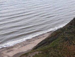 A coastal landscape with a sandy beach and a grassy cliff. - 5 Star Holiday Home in Vinderup (Vinderup)