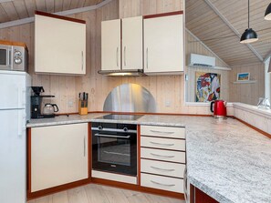 A kitchen with wooden cabinets, a stainless steel range hood, a built-in oven, and a granite countertop. - 5 Star Holiday Home in Vinderup (Vinderup)