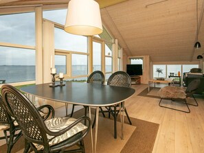 A dining area with a table and chairs, a television, and a view of the sea. - 5 Star Holiday Home in Vinderup (Vinderup)