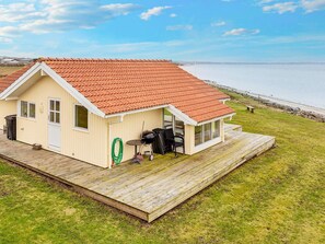 A coastal house with a red-tiled roof, a wooden deck, and a view of the sea. - 5 Star Holiday Home in Vinderup (Vinderup)