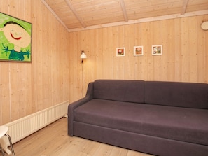A room with wooden walls, a purple sofa, a small table, and a radiator. - 5 Star Holiday Home in Vinderup (Vinderup)