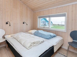 A room with a bed, a chair, a window, and a view of a house. - 5 Star Holiday Home in Vinderup (Vinderup)