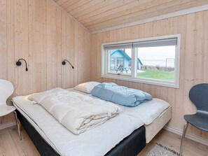 A bedroom with a bed, a window, a chair, and a wall-mounted lamp. - 5 Star Holiday Home in Vinderup (Vinderup)