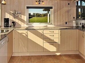 A modern kitchen with wooden cabinets, a large window, and a view of a green field. - 4 Star Holiday Home in Ansager (Ansager)