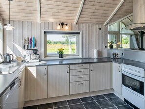 A modern kitchen with wooden cabinets, a large window, and a view of the outdoors. - 4 Star Holiday Home in Ansager (Ansager)