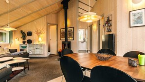 Ein geräumiger Raum mit Holzboden, einem Essbereich mit Holztisch und schwarzen Stühlen, einem Sofa und einer kleinen Küche im Hintergrund.