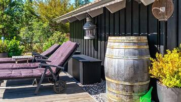 Una terraza de madera con sillones de descanso y un barril grande.