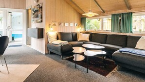 Ein modernes Wohnzimmer mit einer Eckcouch, zwei runden Tischen und einem großen Fenster mit Vorhängen.