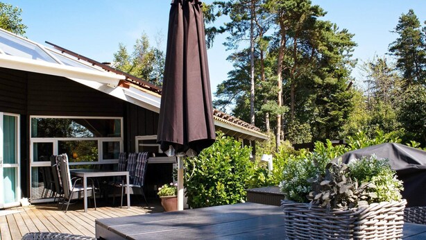 Eine Terrassengruppe im Freien mit Tisch, Stühlen und einem Sonnenschirm.