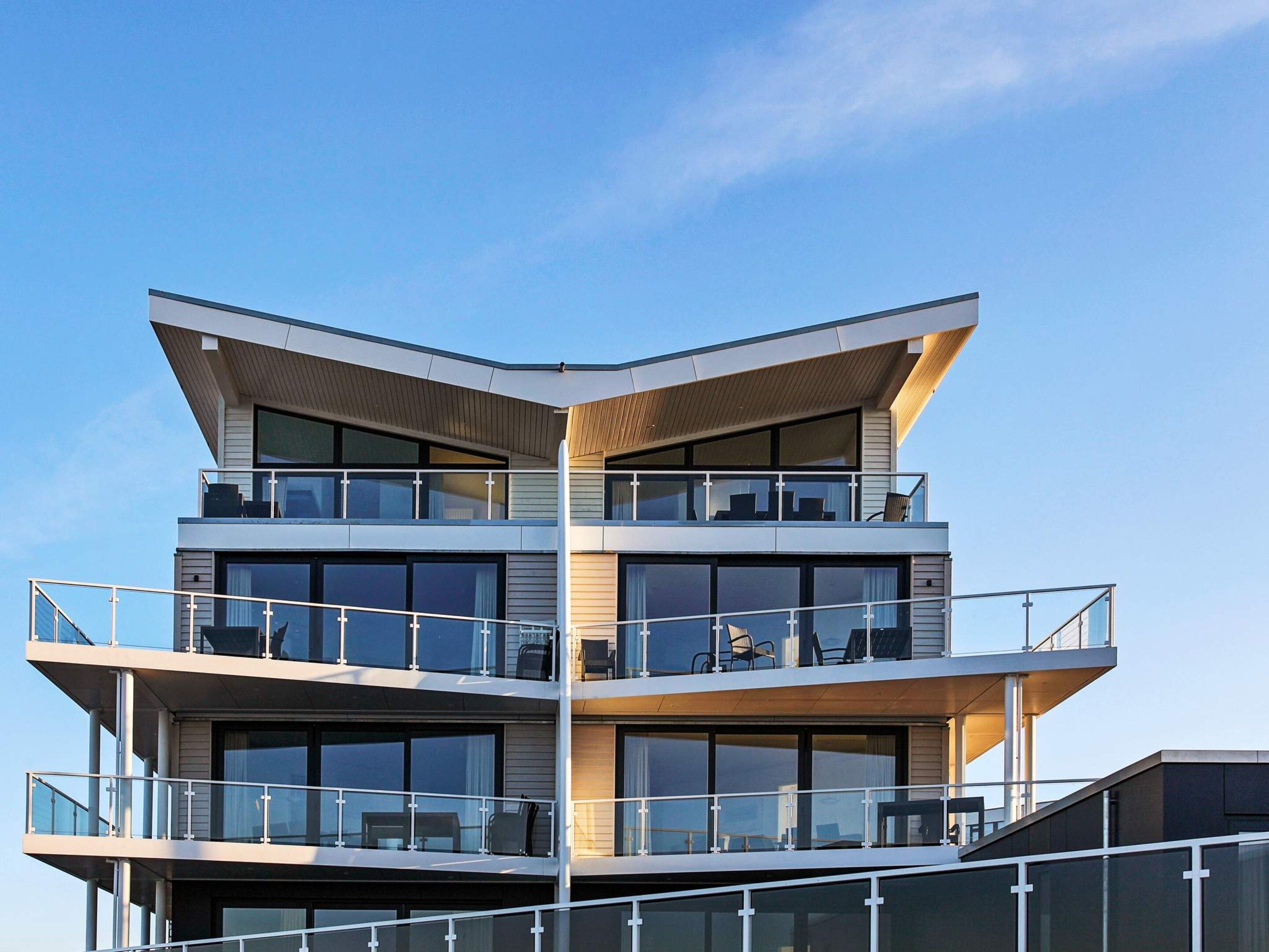 A multi-story building with balconies, large windows, and a modern architectural design.
