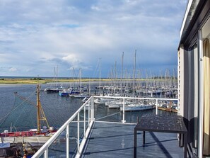 A marina with multiple boats docked, a crane, and a building with a balcony overlooking the water. - Holiday Home in Wendtorf (Schönberg)