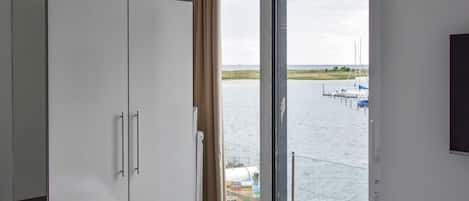 A room with a large window, a wardrobe, and a bed.