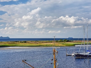 A marina with boats, a dock, and a distant ship on the horizon. - Holiday Home in Wendtorf (Schönberg)