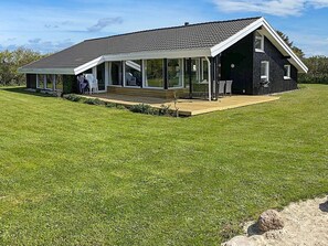 A modern house with a large deck, a covered patio, and a well-maintained lawn. - 4 Star Holiday Home in Hjorring (Hjørring)