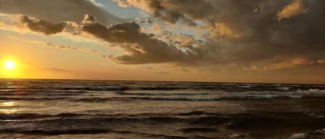 A beach with waves and a sunset.