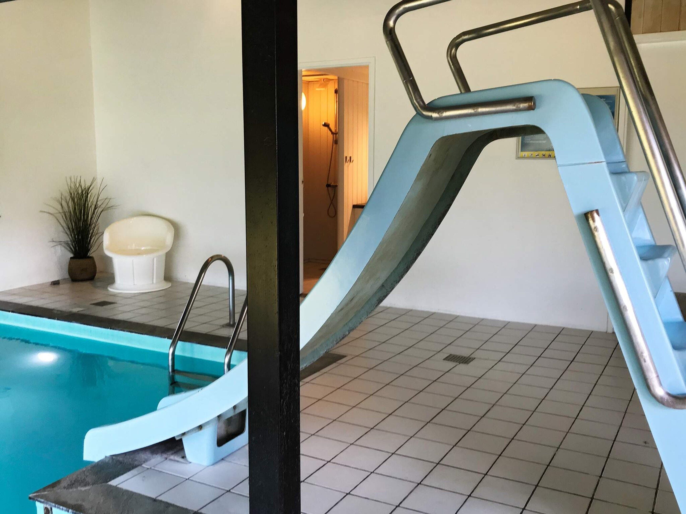A pool area with a diving board and a potted plant.