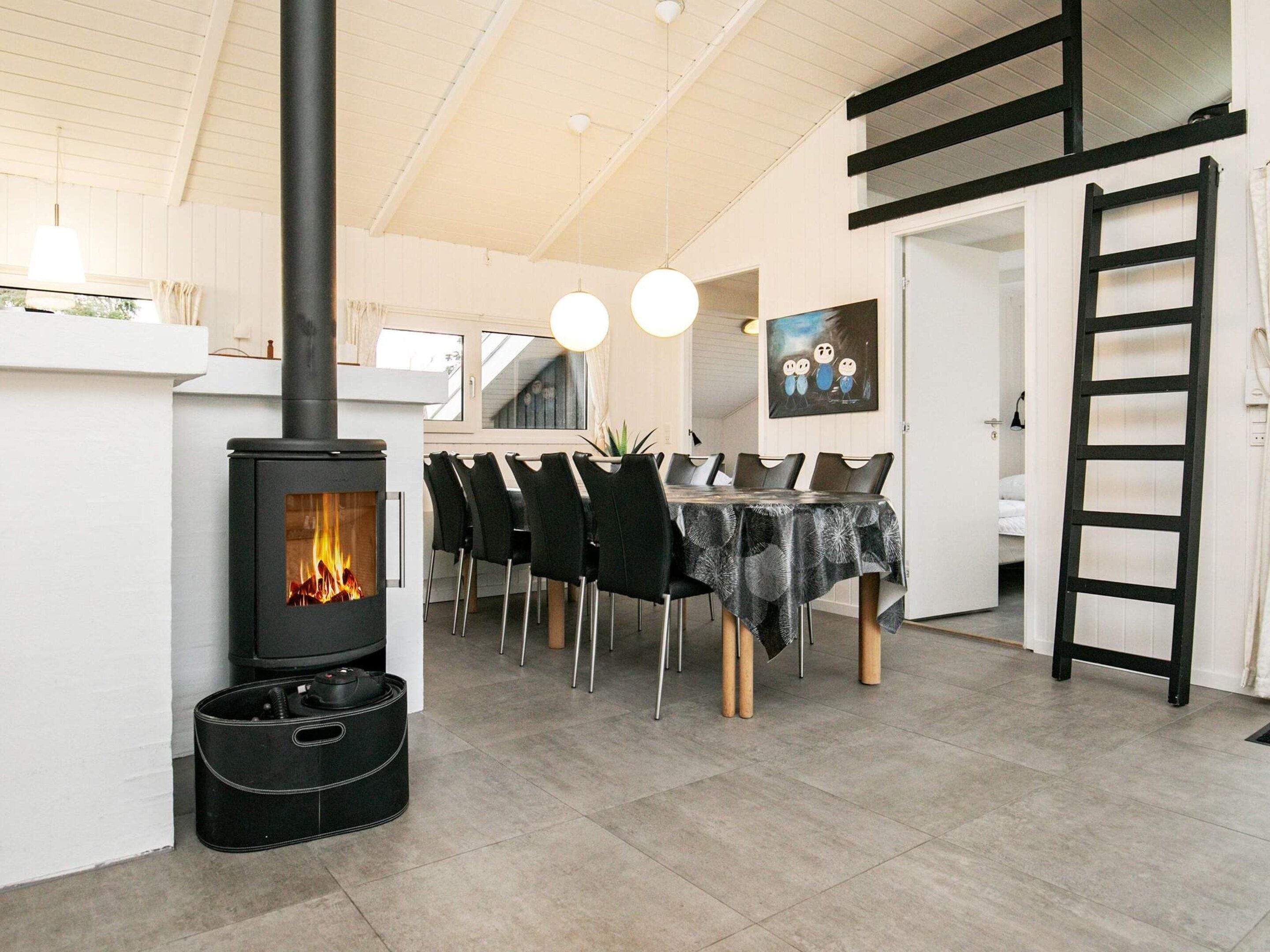 A dining area with a black stove, chairs, and a table with a patterned tablecloth.