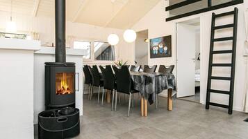 A dining area with a black stove, chairs, and a table with a patterned tablecloth.