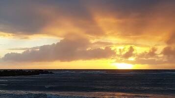 A sunset over the ocean with waves crashing onto the shore.