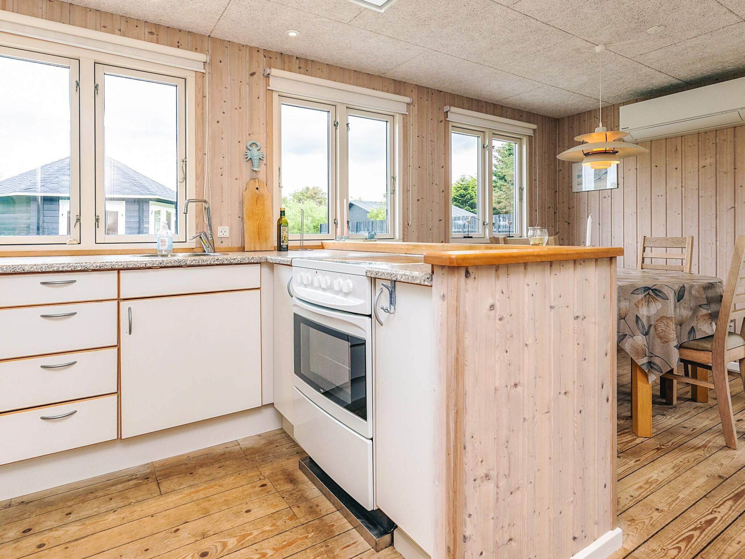 A kitchen with wooden paneling, a white stove, and a dining area with a table and chairs.
