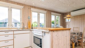 Una cocina con paneles de madera, una estufa blanca y un comedor con mesa y sillas.