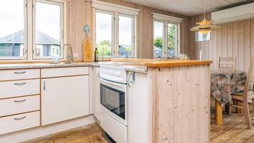 A kitchen with wooden paneling, a white stove, and a dining area with a table and chairs.