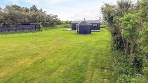 A grassy backyard with two small sheds and a wooden fence.
