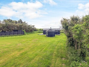 A grassy backyard with two small sheds and a wooden fence.