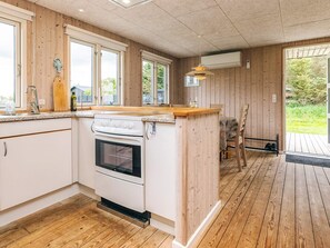 A kitchen with wooden walls, a central island, and a dining area with a table and chairs.
