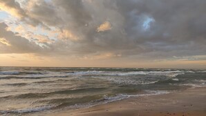 A beach with waves and a cloudy sky.