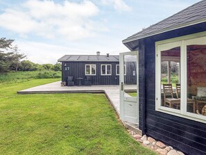 A black house with a number 17 on the side, a patio with chairs, and a grassy yard. - Lovely Holiday Home in LÃ¸nstrup near Sea (Hjørring)