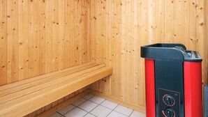 A sauna room with wooden walls, a bench, and a sauna machine. - 5 Star Holiday Home in Lokken (Lokken)