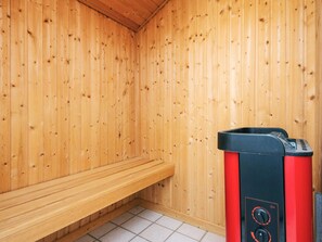 Ein Saunaraum mit Holzwänden, einer Sitzbank und einer Saunaanlage.