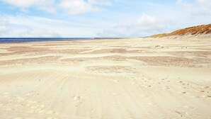 A wide sandy beach with footprints and dunes in the background. - 5 Star Holiday Home in Lokken (Lokken)