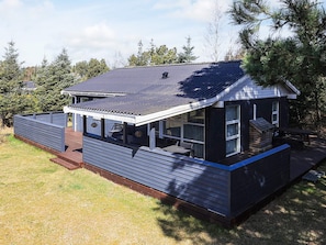 A modern house with a covered porch, a deck, and a large window.