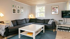 A modern living room with a sectional sofa, a white coffee table, and a flat-screen TV.
