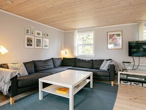 A modern living room with a sectional sofa, a white coffee table, and a flat-screen TV. - 4 Star Holiday Home in Vaeggerlose (Vaeggerlose)