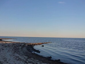 A beach with calm water, a rocky shoreline, and a clear sky. - 4 Star Holiday Home in Vaeggerlose (Vaeggerlose)