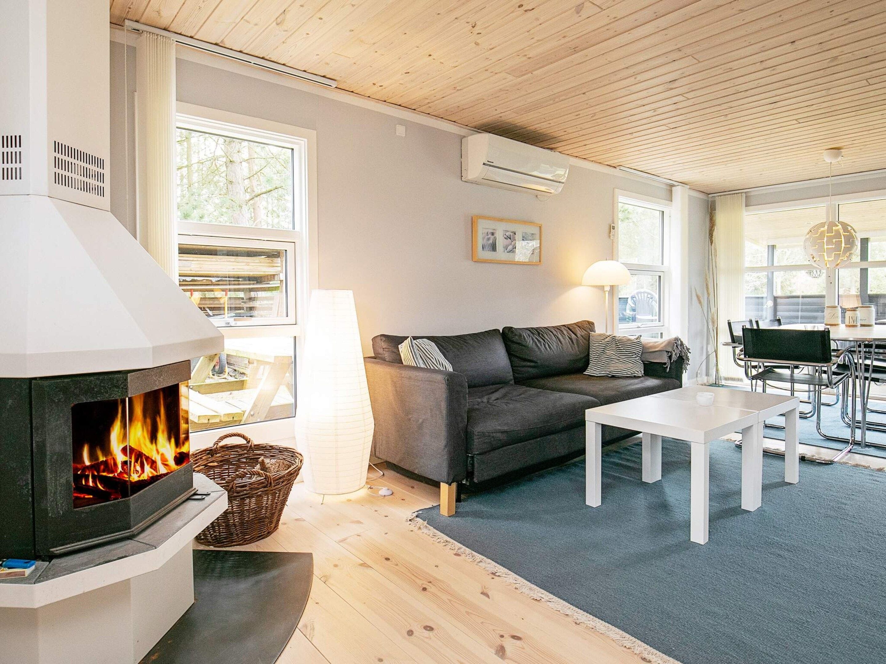 A cozy living room with a fireplace, a sofa, a coffee table, and a dining area with chairs.