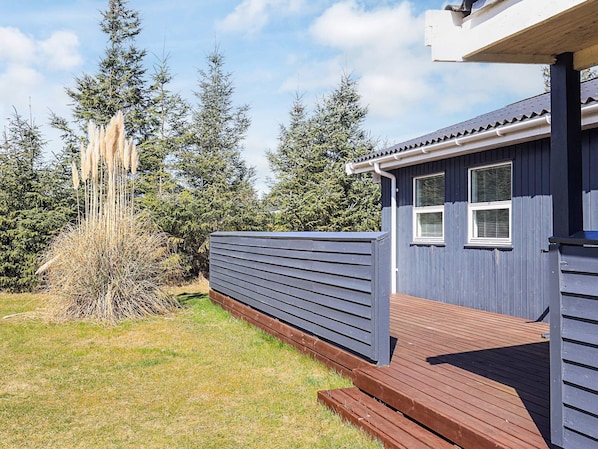 A blue building with a wooden deck and a window.