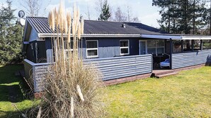 A single-story house with a dark blue exterior, a satellite dish, and a covered porch area.