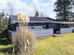 A single-story house with a dark blue exterior, a satellite dish, and a covered porch area. - 4 Star Holiday Home in Vaeggerlose (Vaeggerlose)