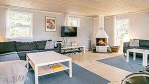 A modern living room with a fireplace, a flat-screen TV, and a sofa.
