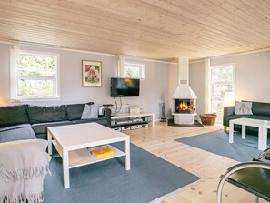 A modern living room with a fireplace, a flat-screen TV, and a sofa. - 4 Star Holiday Home in Vaeggerlose (Vaeggerlose)