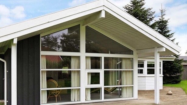 A modern house with a large glass door and windows, a wooden deck, and a grassy yard. - 6 Person Holiday Home in Hejls-by Traum (Hejls)